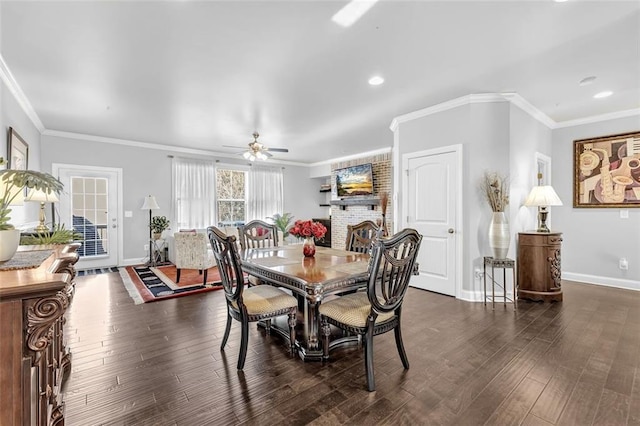 dining space with ornamental molding, a brick fireplace, dark wood-style flooring, and baseboards