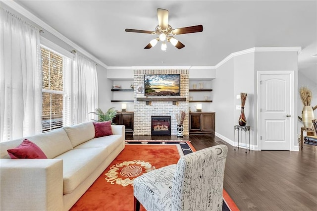 living area with a brick fireplace, crown molding, baseboards, and wood finished floors