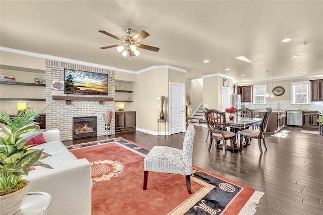 living room with baseboards, stairway, dark wood-style flooring, crown molding, and a fireplace