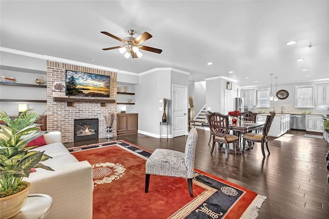 living room featuring dark wood-type flooring, stairway, a fireplace, and crown molding