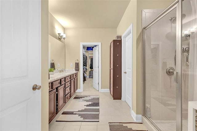 full bath featuring baseboards, tile patterned flooring, a walk in closet, vanity, and a shower stall