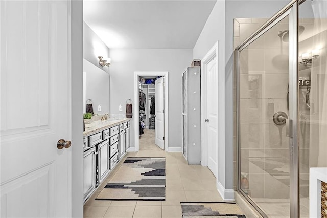 bathroom with a stall shower, baseboards, tile patterned flooring, a spacious closet, and vanity