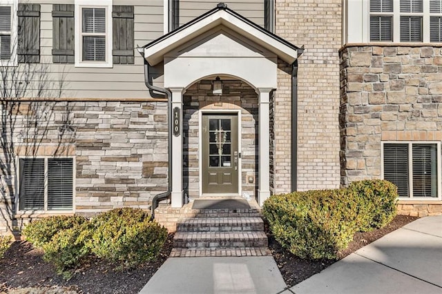 view of exterior entry with stone siding and brick siding