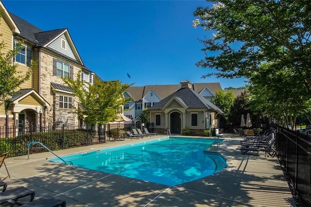 pool with a patio area and fence