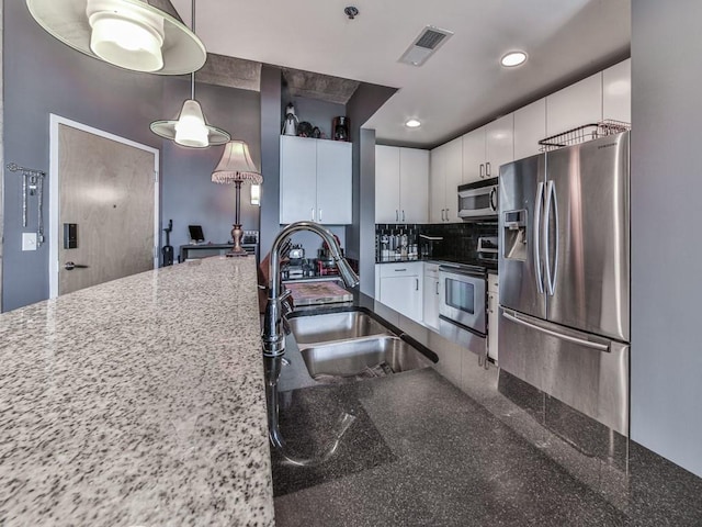 361 17th St NW Unit 1121, Atlanta, GA 30363 - kitchen with hanging light fixtures, appliances with stainless steel finishes, sink, white cabinetry, and dark stone counters