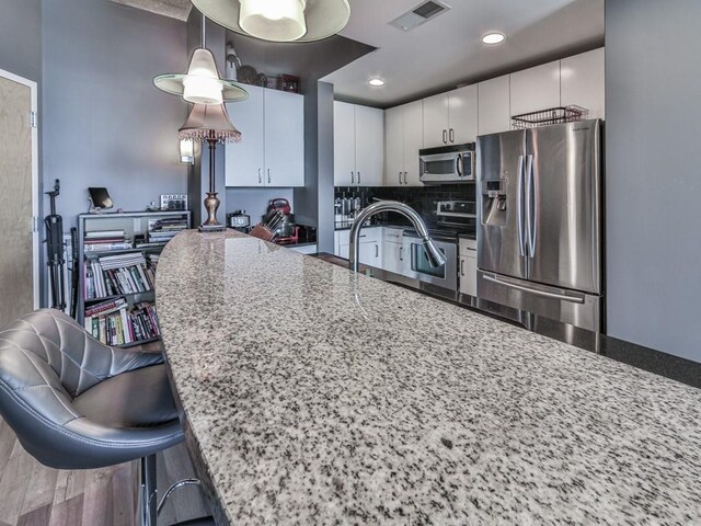 361 17th St NW Unit 1121, Atlanta, GA 30363 - kitchen with pendant lighting, appliances with stainless steel finishes, white cabinetry, dark stone countertops, and a breakfast bar