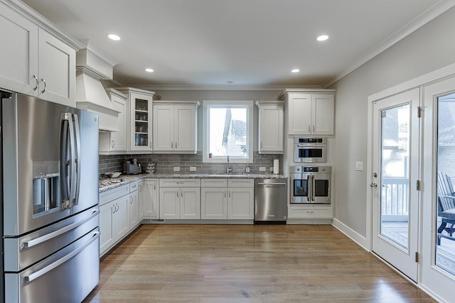 3441 Shoreland Dr, Buford, GA 30518 - kitchen featuring appliances with stainless steel finishes, ornamental molding, decorative backsplash, light stone counters, and white cabinets