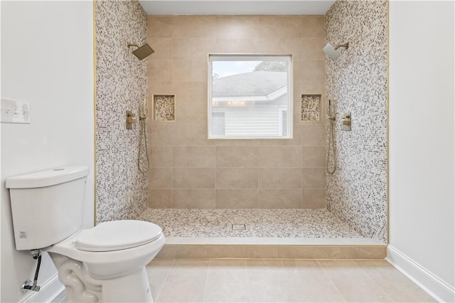 bathroom with tile patterned flooring, toilet, and tiled shower