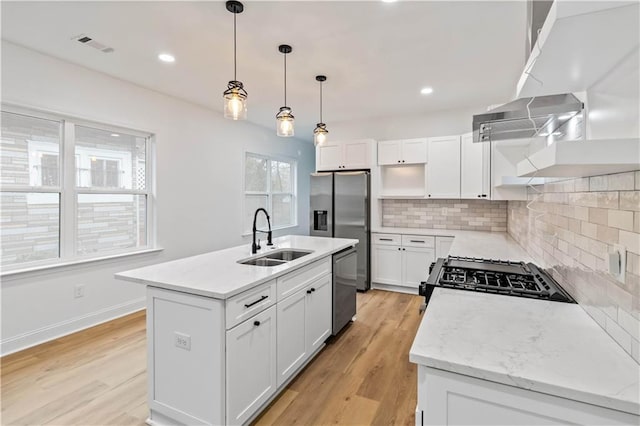 kitchen with backsplash, a kitchen island with sink, sink, appliances with stainless steel finishes, and white cabinetry