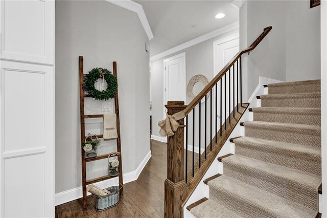 staircase featuring crown molding and dark hardwood / wood-style flooring