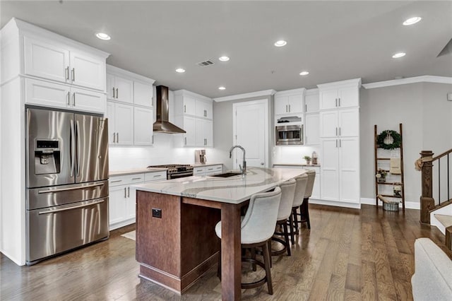 kitchen featuring wall chimney range hood, light stone counters, stainless steel appliances, sink, and dark hardwood / wood-style floors