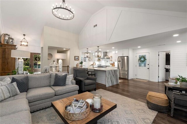 kitchen with wall chimney range hood, high quality appliances, a breakfast bar, a sink, and a peninsula