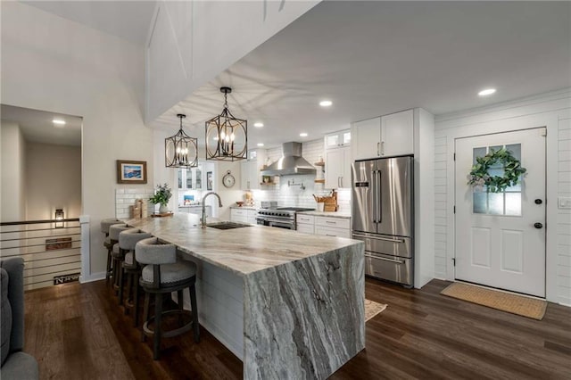 kitchen featuring a peninsula, a barn door, white cabinetry, light stone counters, and a sink