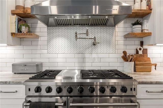 kitchen with wall chimney range hood, dark wood finished floors, a sink, stainless steel appliances, and white cabinetry