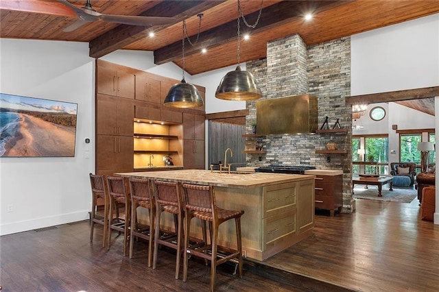 kitchen featuring dark hardwood / wood-style flooring, ceiling fan, wooden ceiling, and a center island with sink