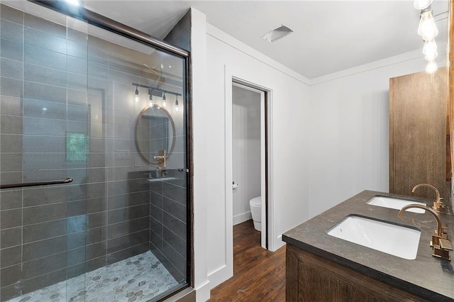 bathroom featuring wood-type flooring, vanity, a shower with shower door, and toilet