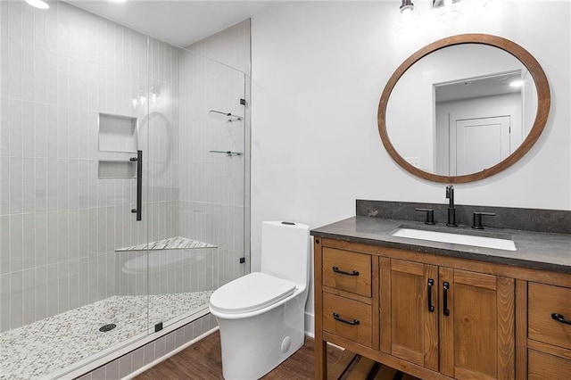 bathroom with a shower with shower door, hardwood / wood-style flooring, vanity, and toilet