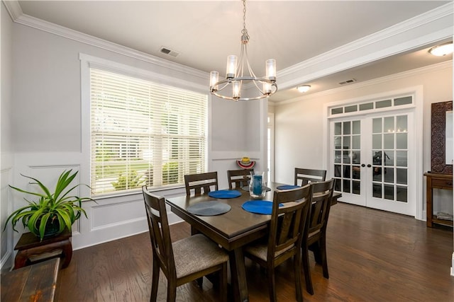 dining space with a chandelier, french doors, dark wood-style flooring, crown molding, and wainscoting
