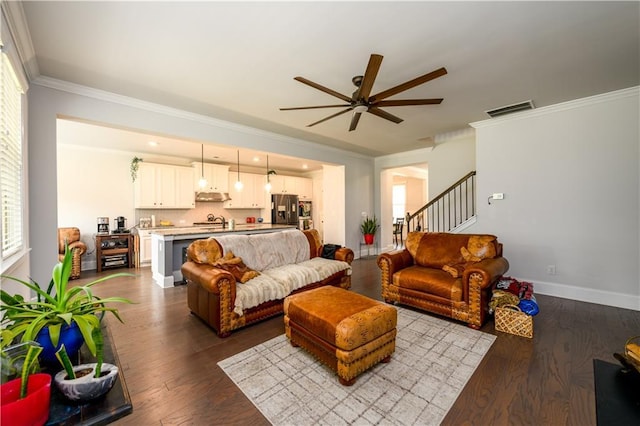 living room featuring ceiling fan, crown molding, dark wood-type flooring, stairs, and baseboards