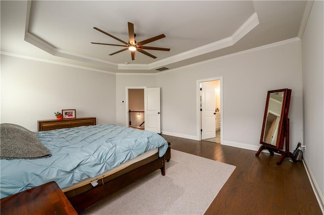 bedroom with a tray ceiling, dark wood-style floors, baseboards, crown molding, and a ceiling fan