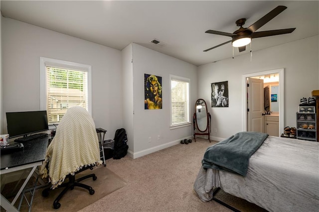 carpeted bedroom featuring baseboards, a desk, ceiling fan, and ensuite bathroom