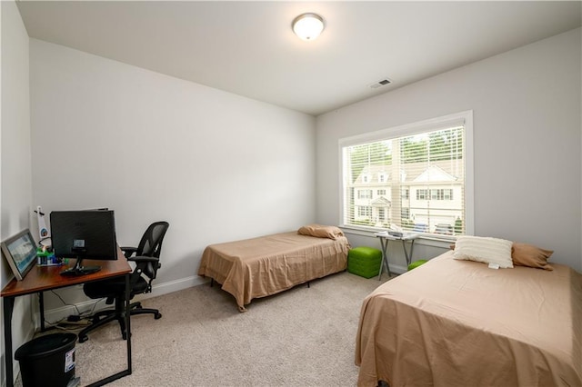 bedroom featuring light colored carpet, an office area, and baseboards