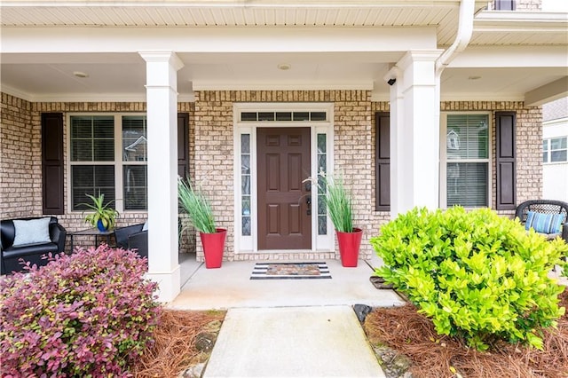 entrance to property featuring covered porch and brick siding