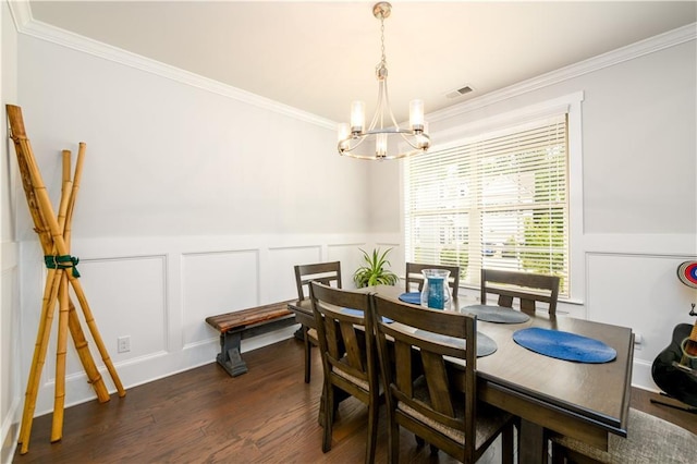dining area featuring a chandelier, ornamental molding, dark wood-style floors, a decorative wall, and wainscoting
