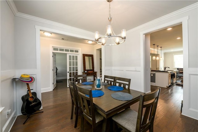 dining area with a chandelier, dark wood finished floors, crown molding, and french doors