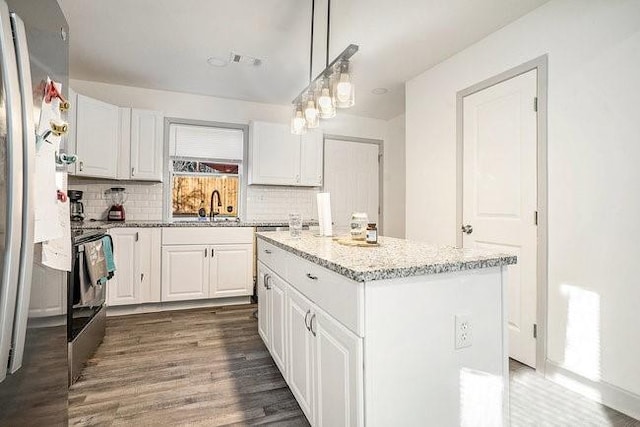 kitchen with a sink, white cabinetry, hanging light fixtures, freestanding refrigerator, and a center island