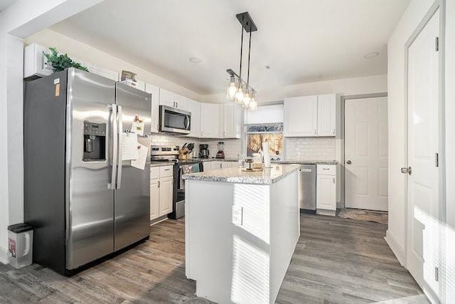 kitchen featuring stainless steel appliances, a center island, white cabinets, and hanging light fixtures