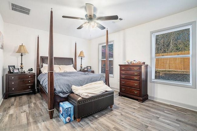 bedroom featuring ceiling fan, light wood finished floors, visible vents, and baseboards