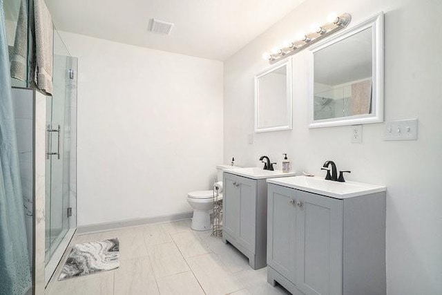 bathroom with a stall shower, baseboards, toilet, two vanities, and a sink