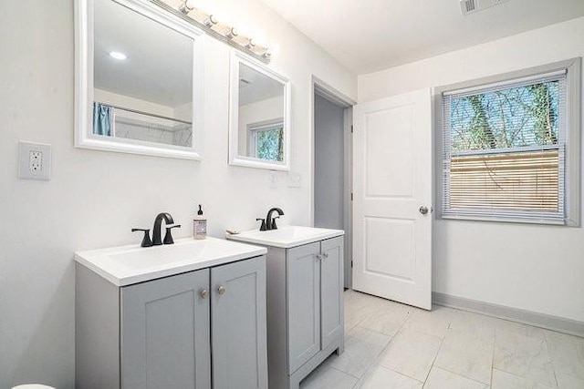 bathroom with plenty of natural light, two vanities, and a sink