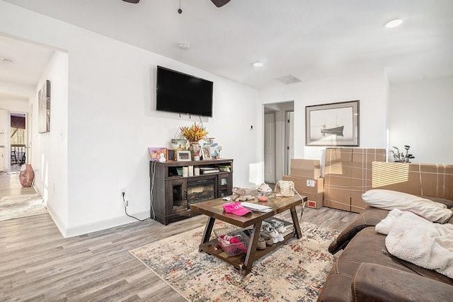 living room featuring light wood-style floors, recessed lighting, a ceiling fan, and a glass covered fireplace