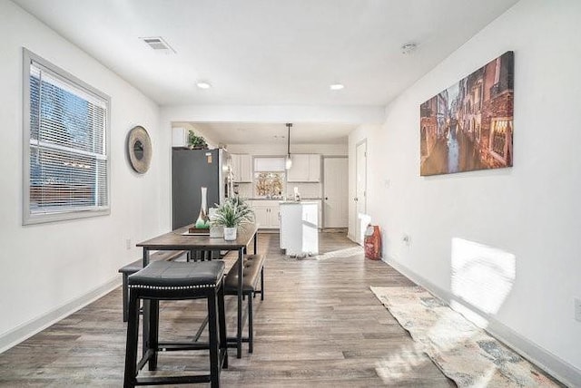 dining space featuring visible vents, plenty of natural light, baseboards, and wood finished floors