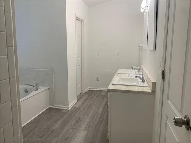 bathroom featuring wood-type flooring, vanity, and a tub