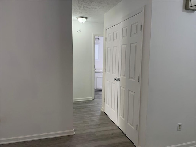 corridor featuring a textured ceiling and dark hardwood / wood-style floors