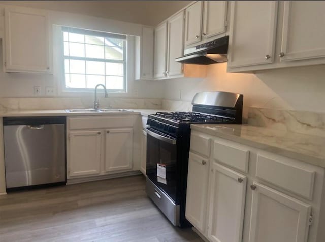 kitchen with sink, light wood-type flooring, light stone counters, white cabinetry, and stainless steel appliances