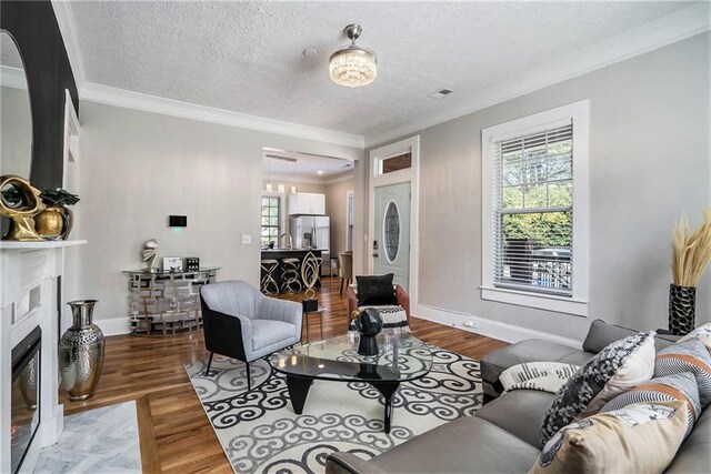 living room featuring a textured ceiling, hardwood / wood-style flooring, and ornamental molding