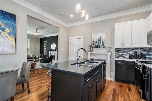 kitchen featuring a textured ceiling, a kitchen island with sink, stainless steel electric stove, sink, and hardwood / wood-style floors