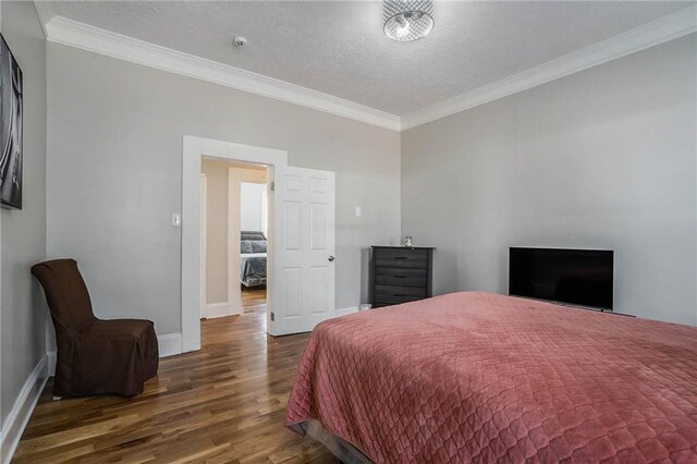 bedroom with crown molding, dark wood-type flooring, and a textured ceiling