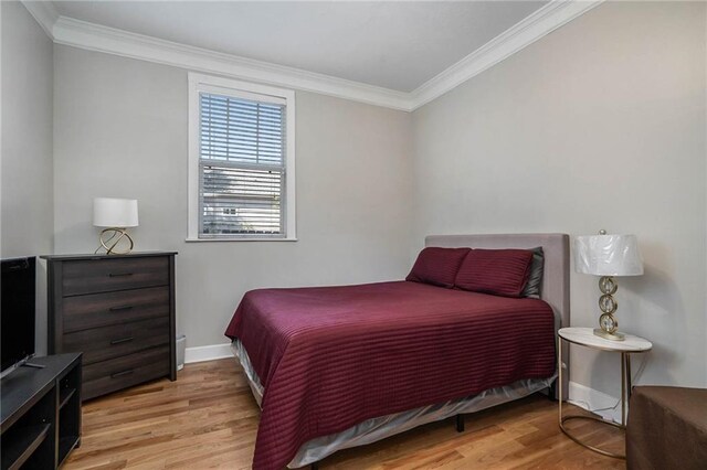 bedroom with crown molding and light wood-type flooring