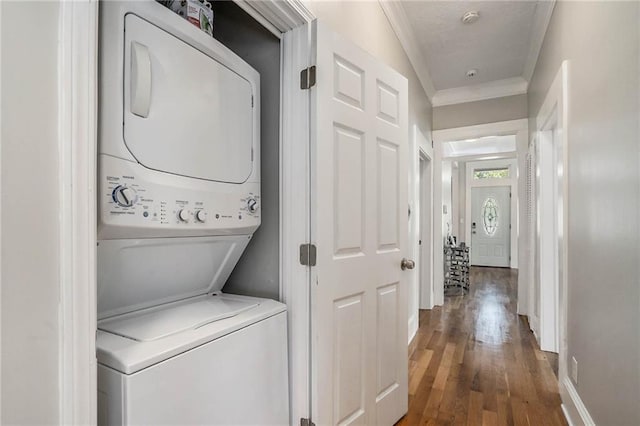 laundry room featuring wood-type flooring, stacked washing maching and dryer, and crown molding