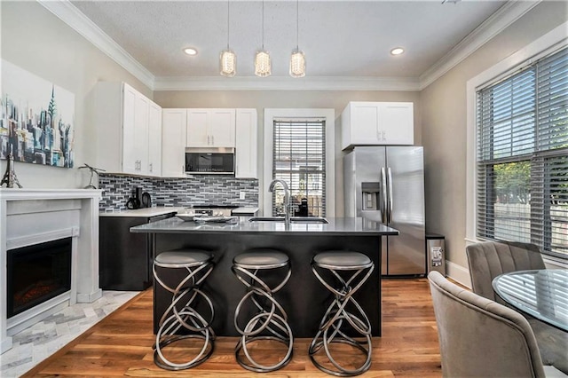 kitchen with white cabinets, sink, a breakfast bar area, a kitchen island, and stainless steel appliances