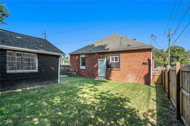 back of property with a yard and central AC unit