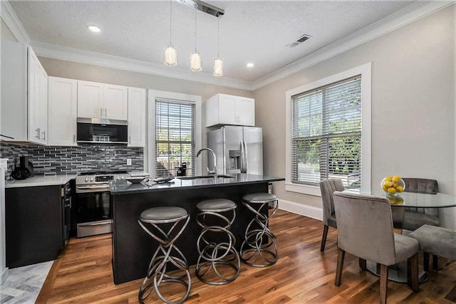 kitchen with sink, stainless steel appliances, a kitchen breakfast bar, hardwood / wood-style floors, and a kitchen island