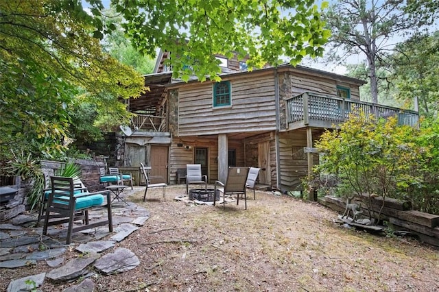 rear view of house featuring a patio, a wooden deck, and a fire pit