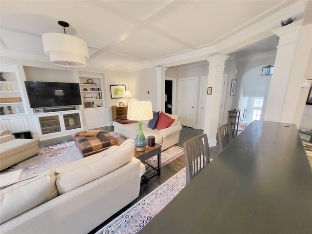 living room with built in shelves, coffered ceiling, crown molding, dark wood-style flooring, and ornate columns