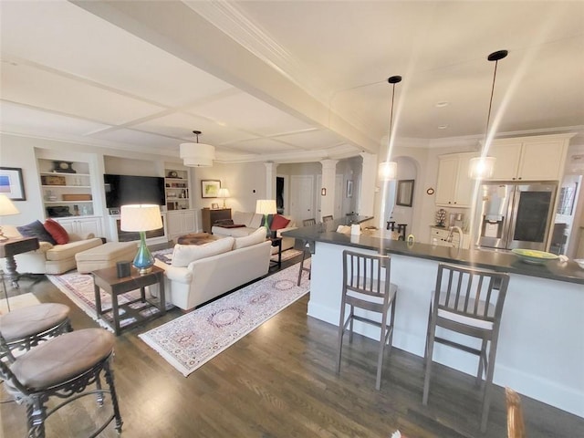 living area with dark wood-type flooring, built in features, arched walkways, crown molding, and ornate columns